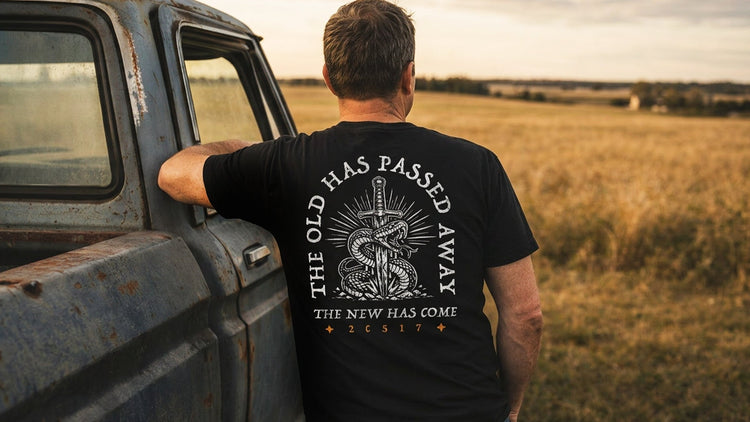 Man leaning on truck wearing TRŪ Wear Black The Old Has Passed Away Sword Tee